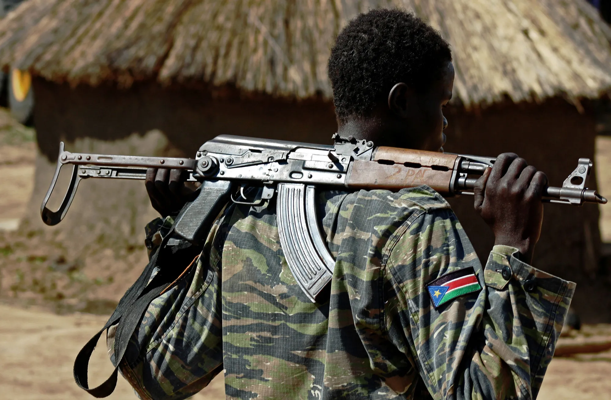 A Sudan People's Liberation Army soldier holds a gun at a containment site outside Juba.