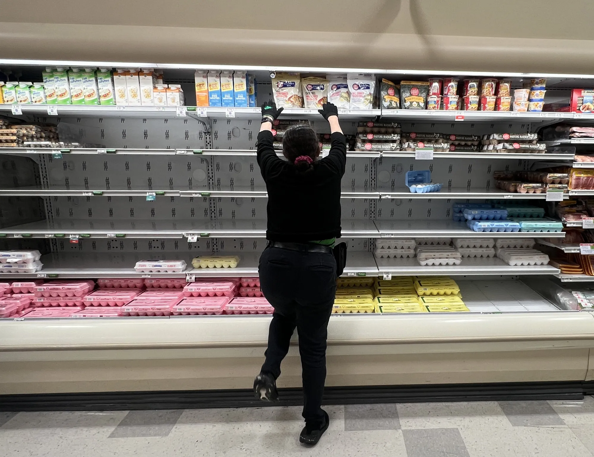 A grocery store worker rearranges items in the depleted egg section in Miami, Florida, on Jan. 23.