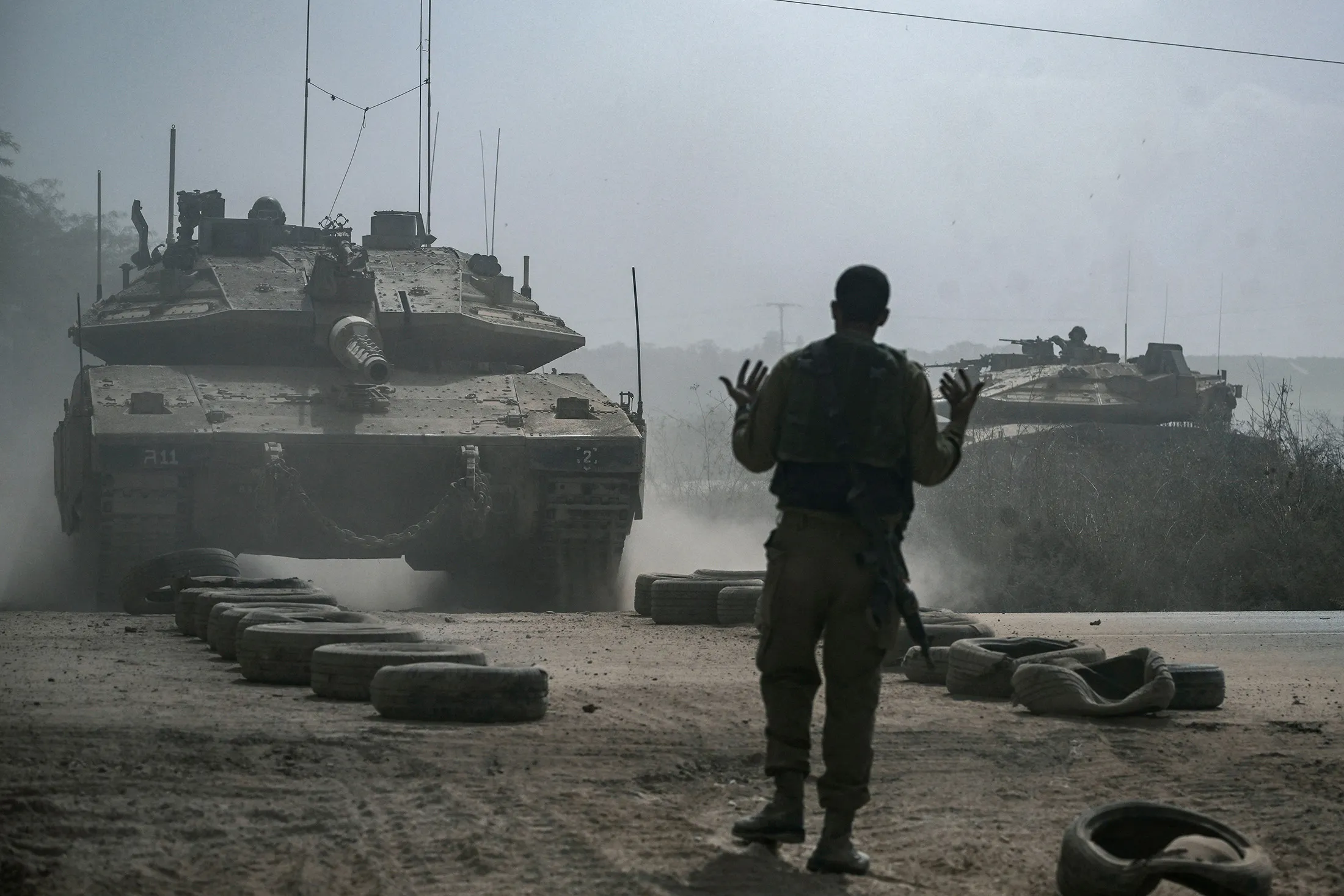 An Israeli soldier directs tanks&nbsp;along the border with the Gaza Strip in southern Israel on Oct. 13.
