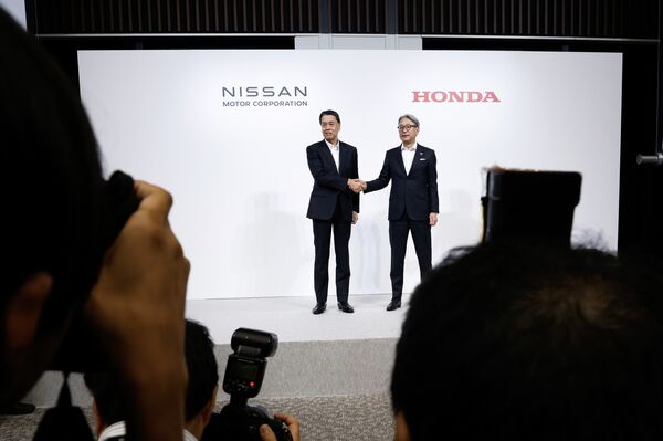 Makoto Uchida, left, and Toshihiro Mibe pose for a photograph during a joint news conference in Tokyo, on Aug. 1.