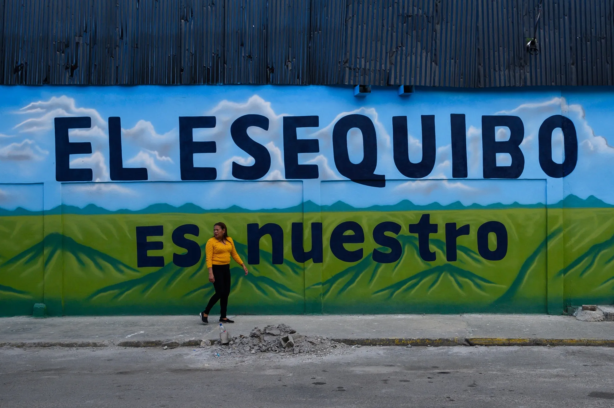 A pedestrian walks past a mural that reads "The Essequibo Is Ours," during a referendum vote in Caracas on Sunday.