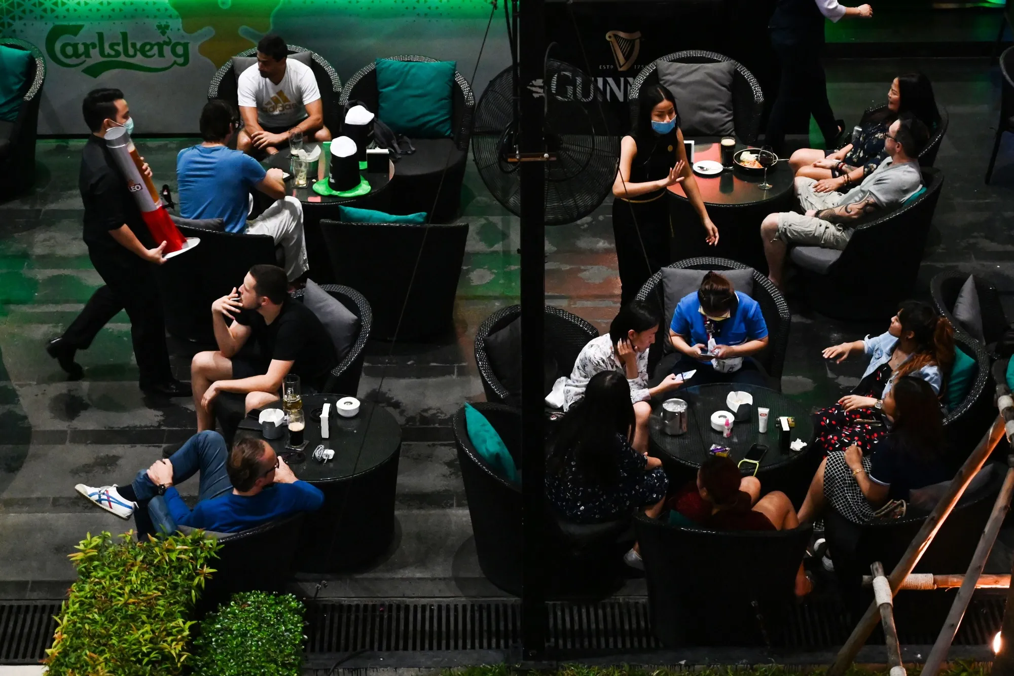Waiters wearing facemasks as a preventive measure against the spread of the COVID-19 Coronavirus serve customers at a hotel bar in Bangkok on March 17.