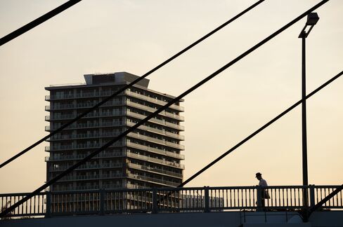 A pedestrian walks past residential buildings in Tokyo, Japan, June 1, 2015.