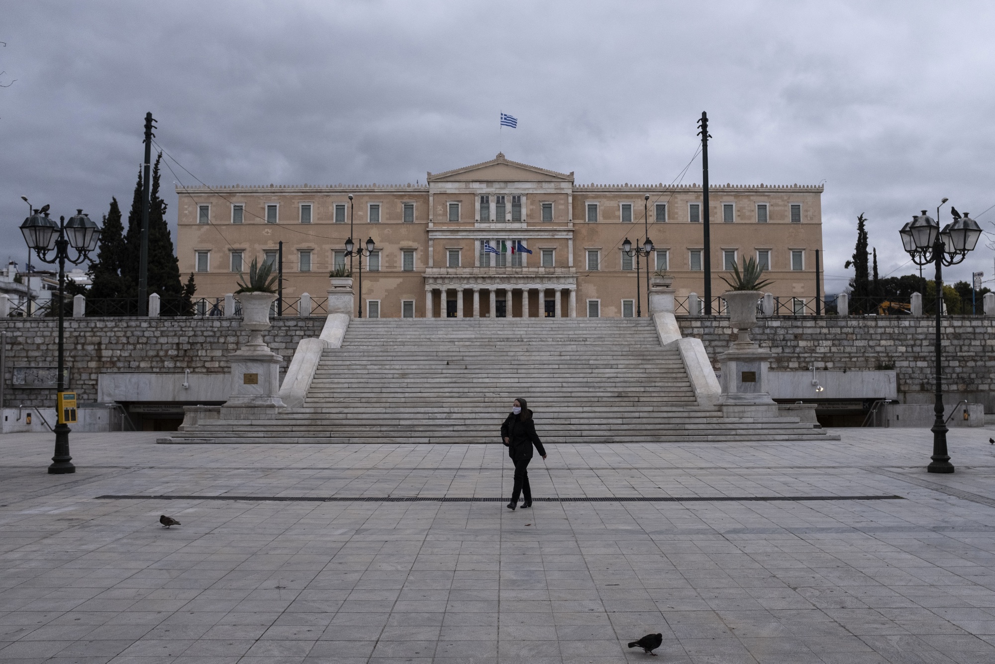 A woman wearing a protective face mask walks at deserted Syntagma square in Athens, Greece, on April 7.