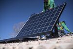 A worker lays down a solar panel on a rooftop in Albuquerque, New Mexico.