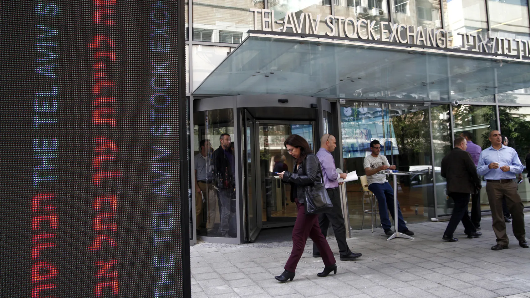 Pedestrians pass the entrance to the Tel Aviv Stock Exchange.

