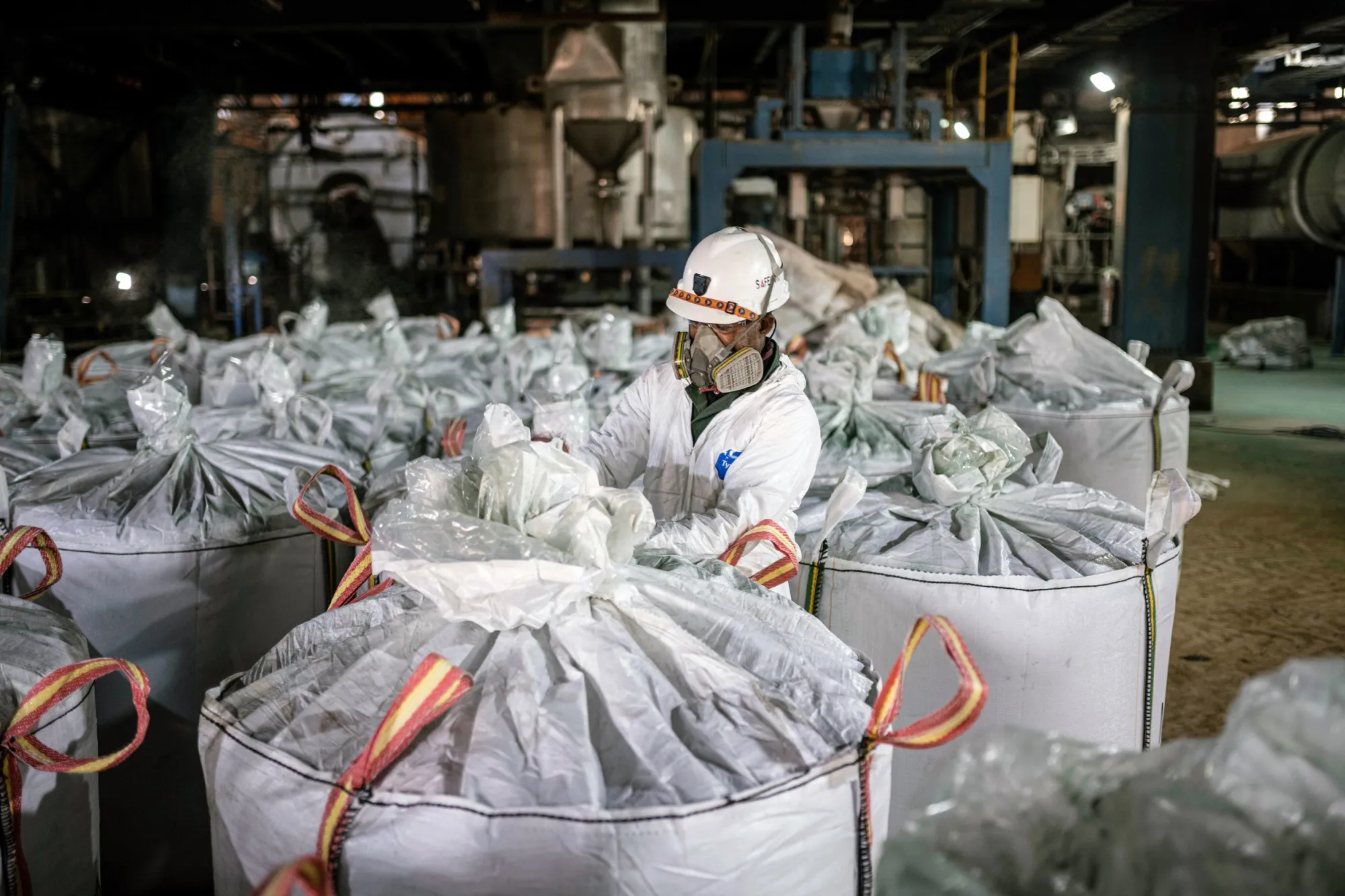 A worker in protective gear seals large bags of cobalt hydroxide at Glencore's Mutanda industrial mine in the Democratic Republic of Congo.