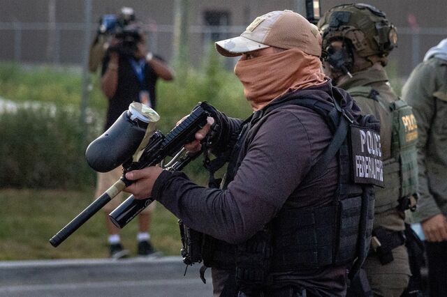 An immigration officer carries a pepper ball gun while patrolling in the Chicago area