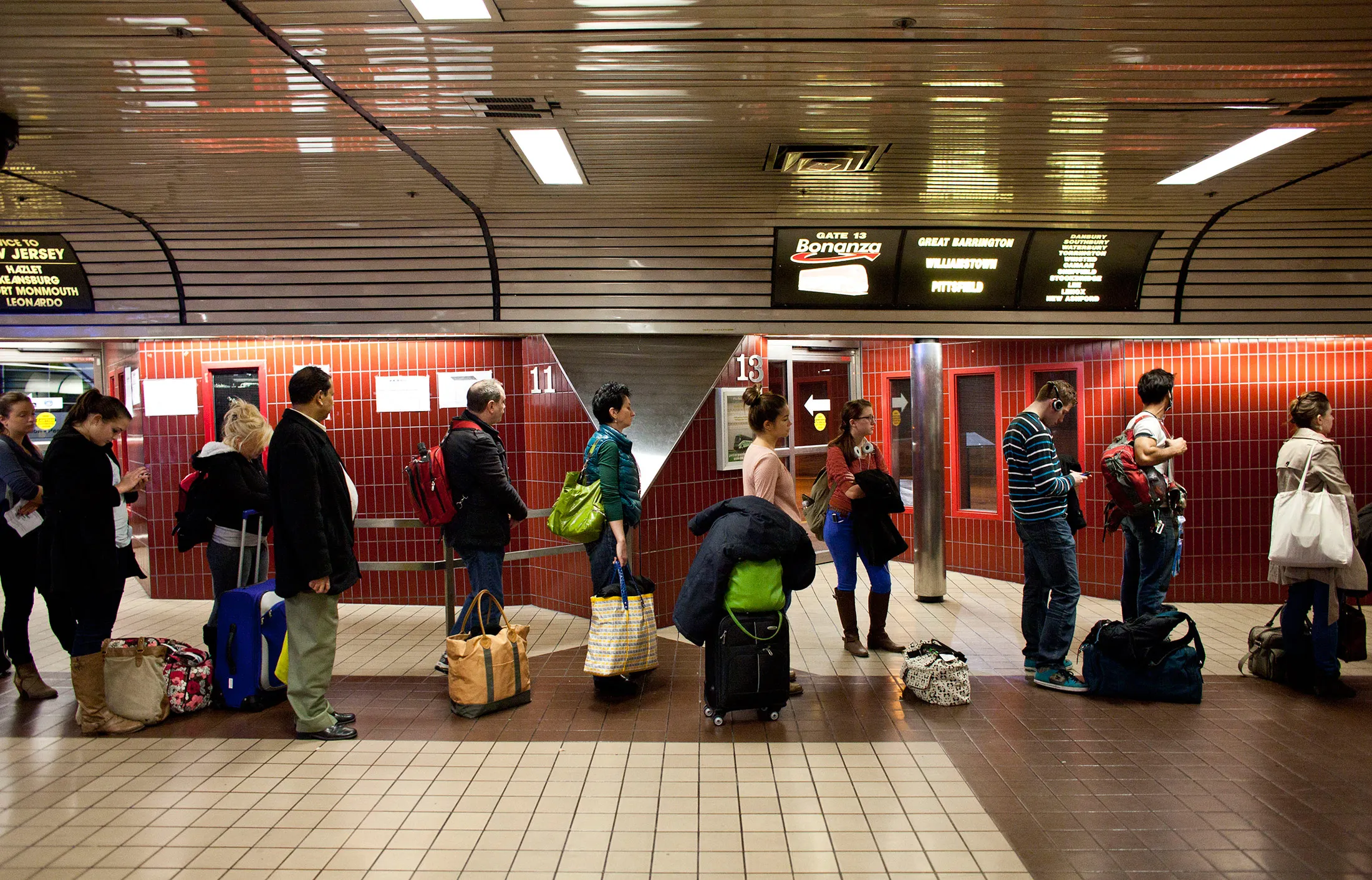 People wait at a gate to board a bus at the New York Port Authority bus terminal in Manhattan
