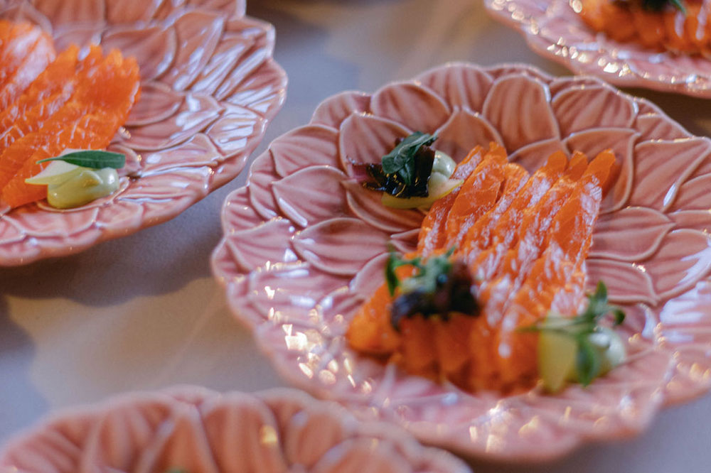 Small plates of thinly sliced cured salmon and garnished with pretty herbs and a tiny dollop of a creamy sauce.