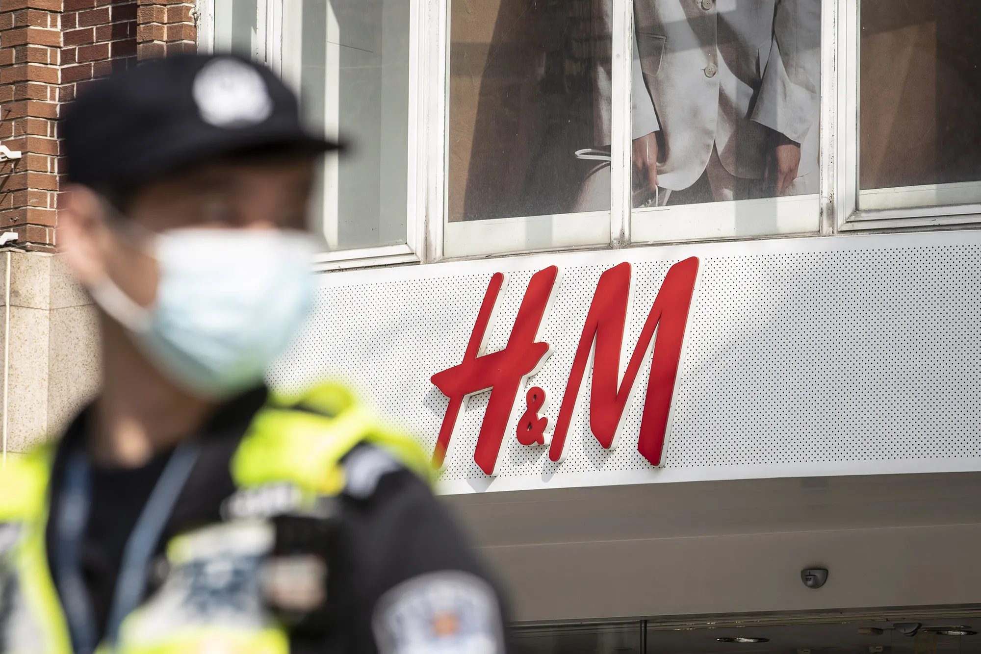 A traffic officer patrols the street in front of an H&amp;M store in Shanghai.