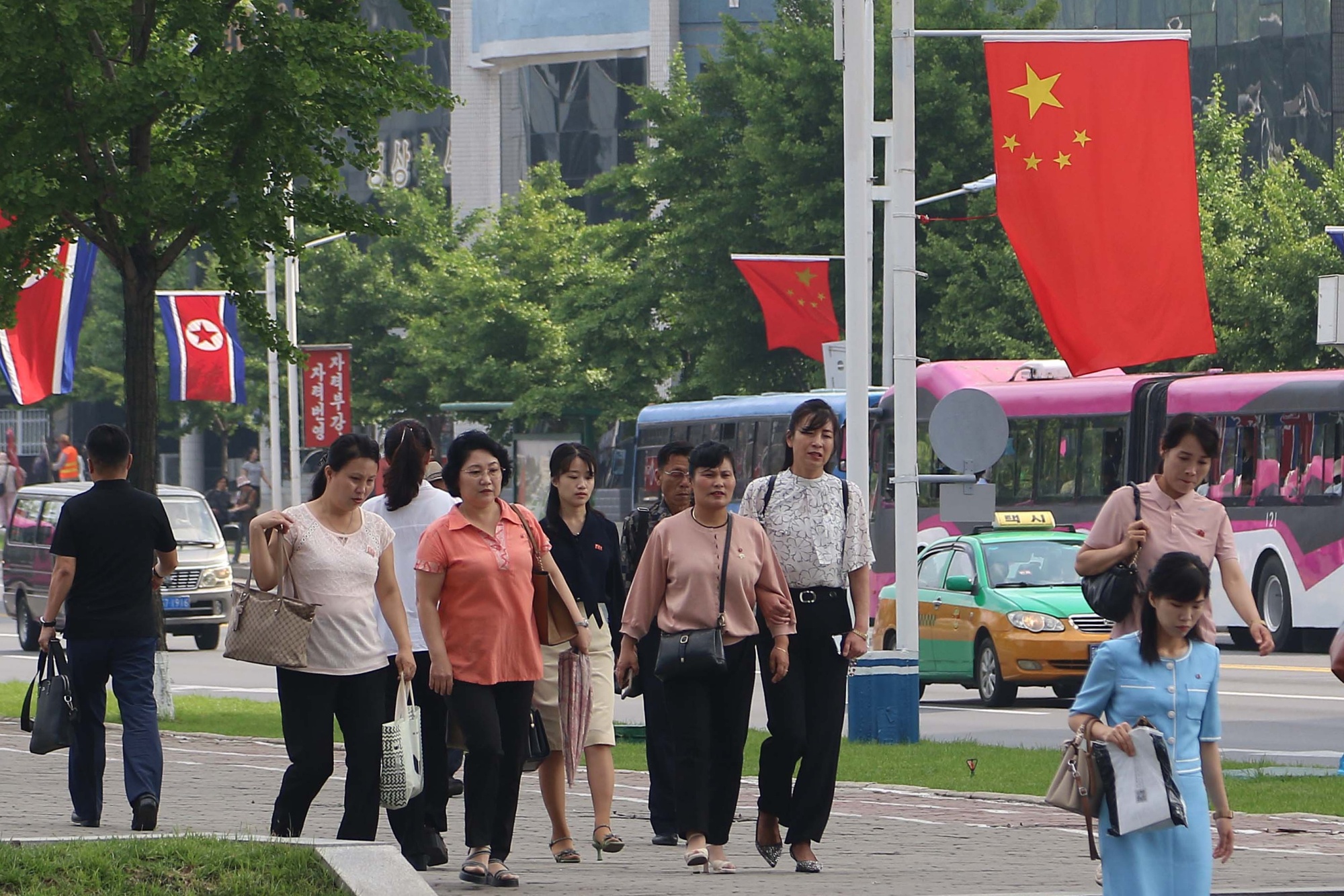 People walk under the flags of China and North Korea in Pyongyang on June 8.