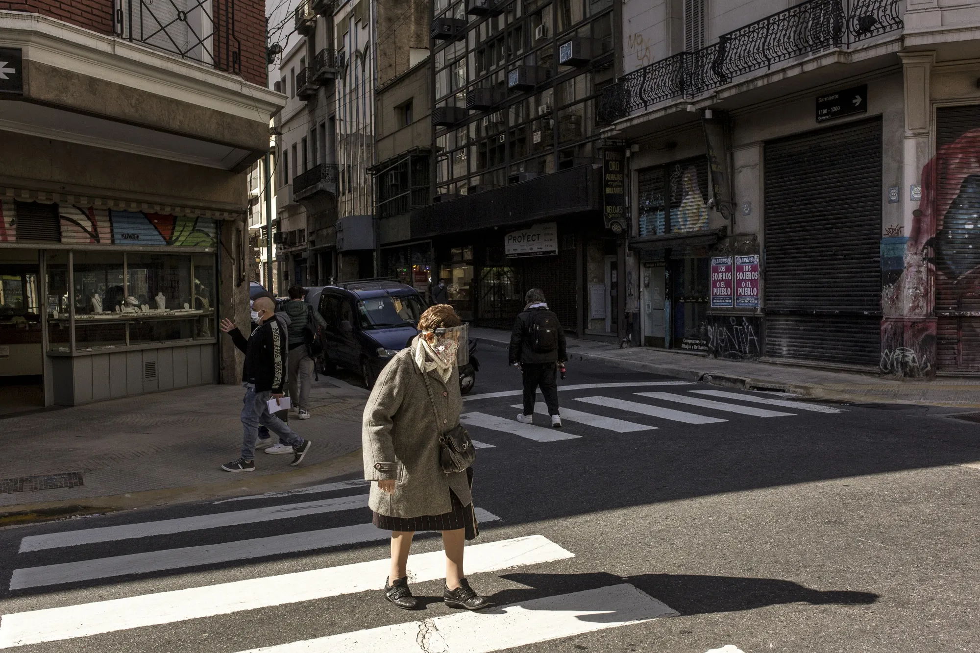 A pedestrian wearing a protective mask and face shield crosses the street in Buenos Aires.