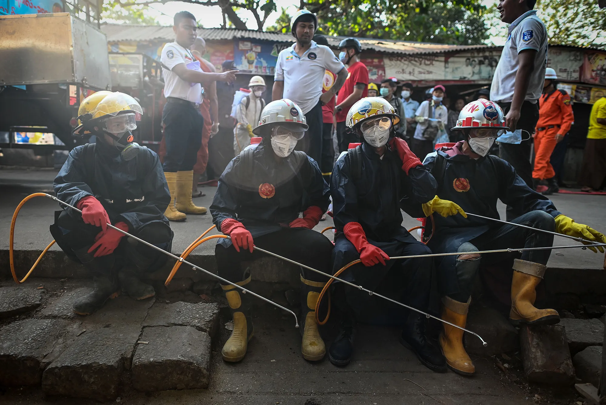 Firefighters take a rest before disinfecting a street market&nbsp;in Yangon on March 27.