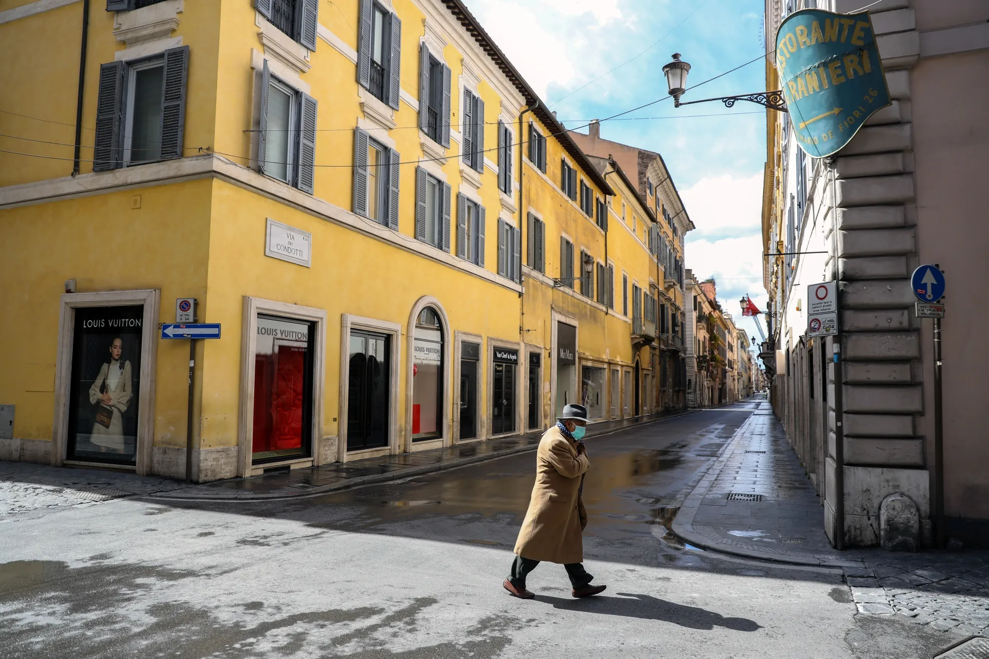 A pedestrian crosses an empty Via Condotti in Rome.
