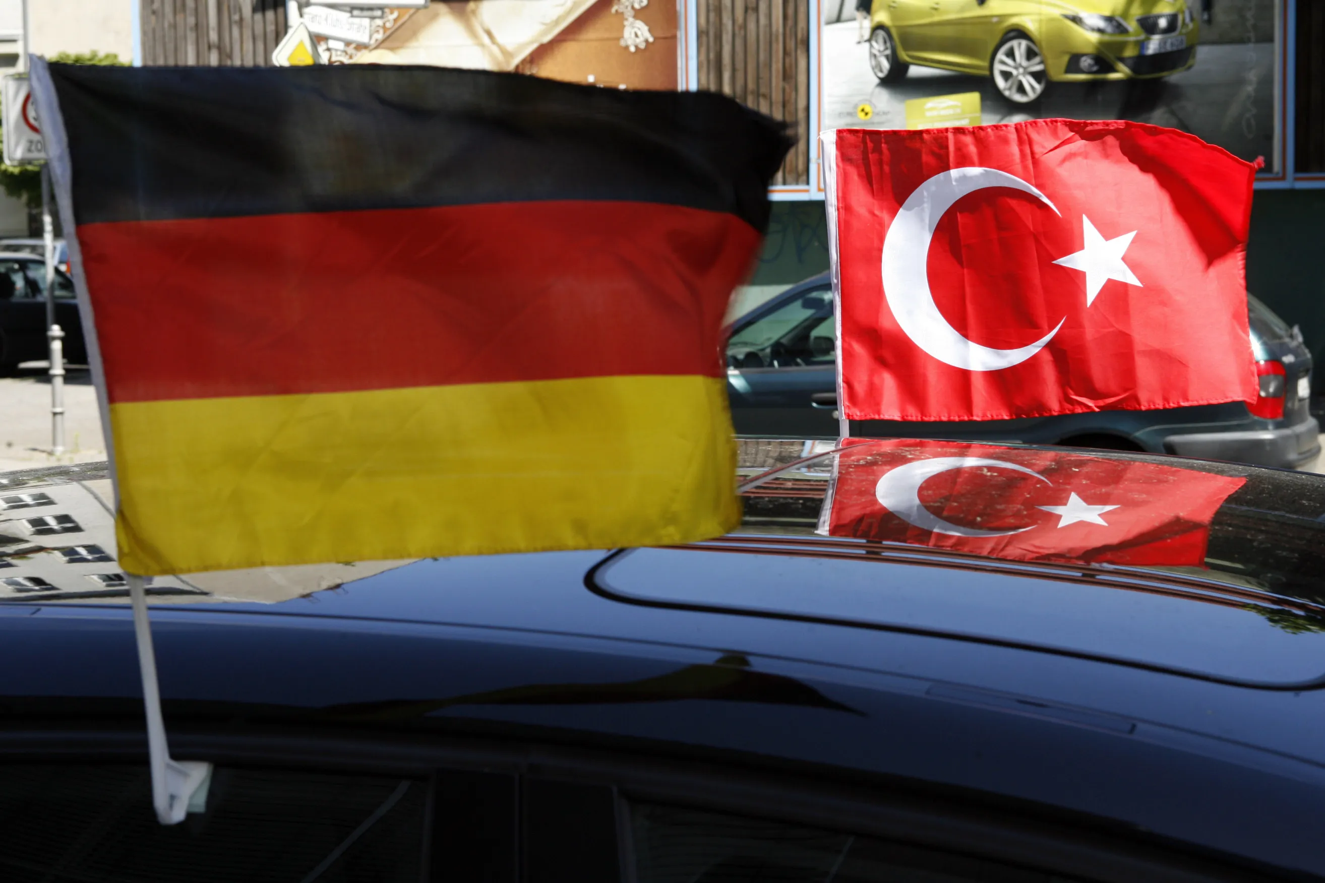 German and Turkish flags, left and right respectively, fly on a car in the Kreuzberg neighborhood of Berlin, Germany.