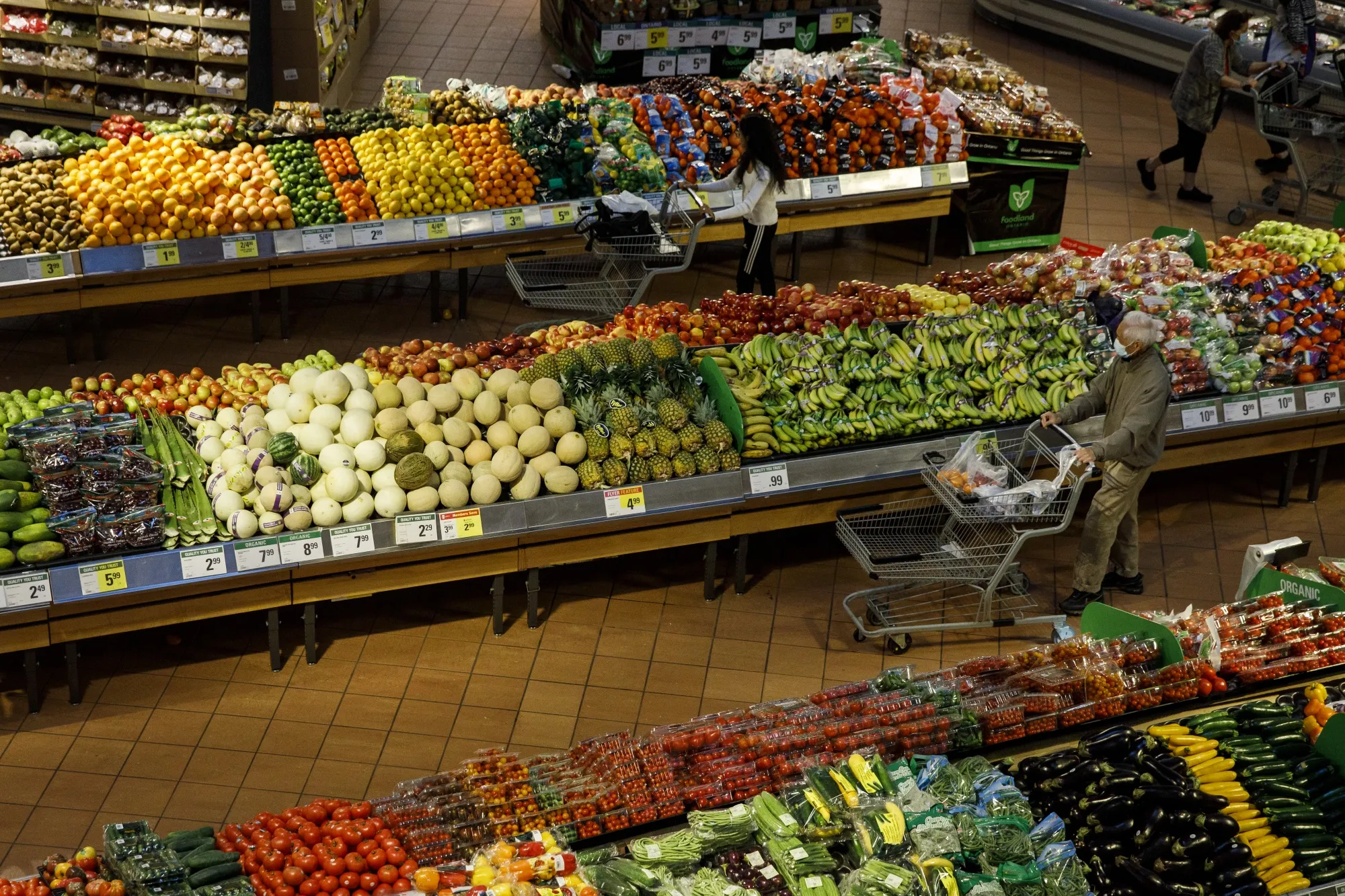 Shoppers walk through produce aisles at a grocery store in Toronto, Ontario.