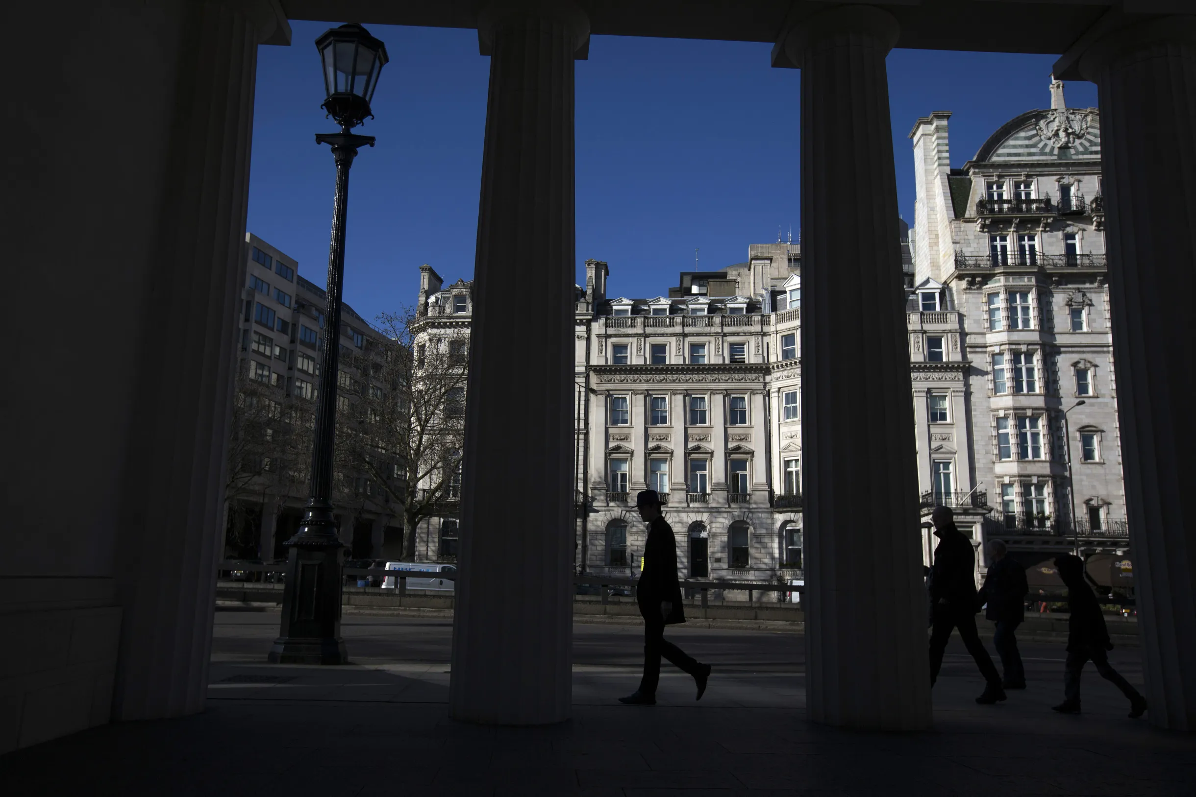 A pedestrian passes a row of buildings in the Mayfair district of London.