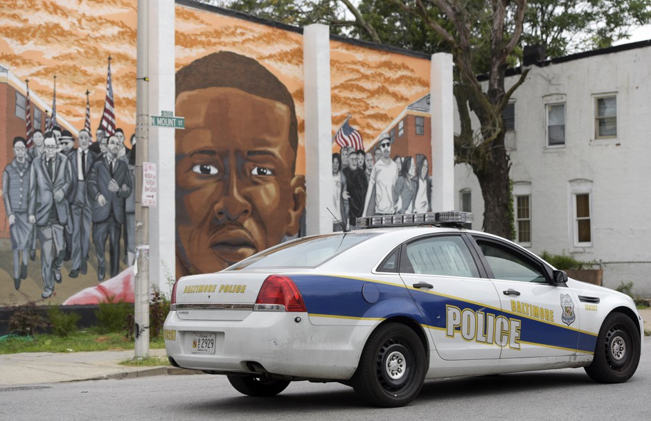A Baltimore police vehicle in front of a mural of Freddie Gray in 2016. The city's police are still making arrests for cannabis possession, even though prosecutors won't file charges.