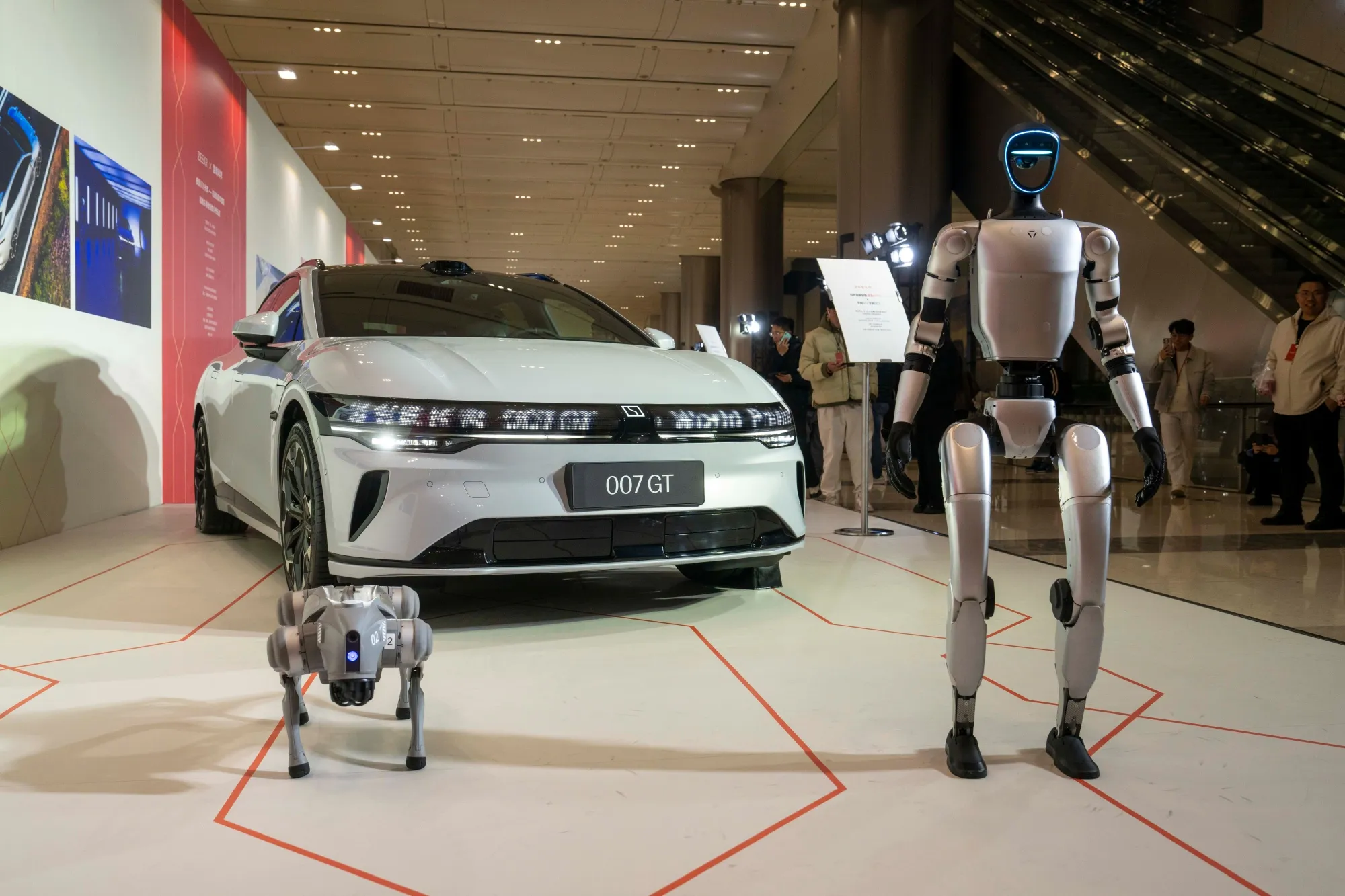 A Unitree Robotics G1 humanoid robot&nbsp;and Go2 robot dog in front of a Zeekr 007 GT EV.