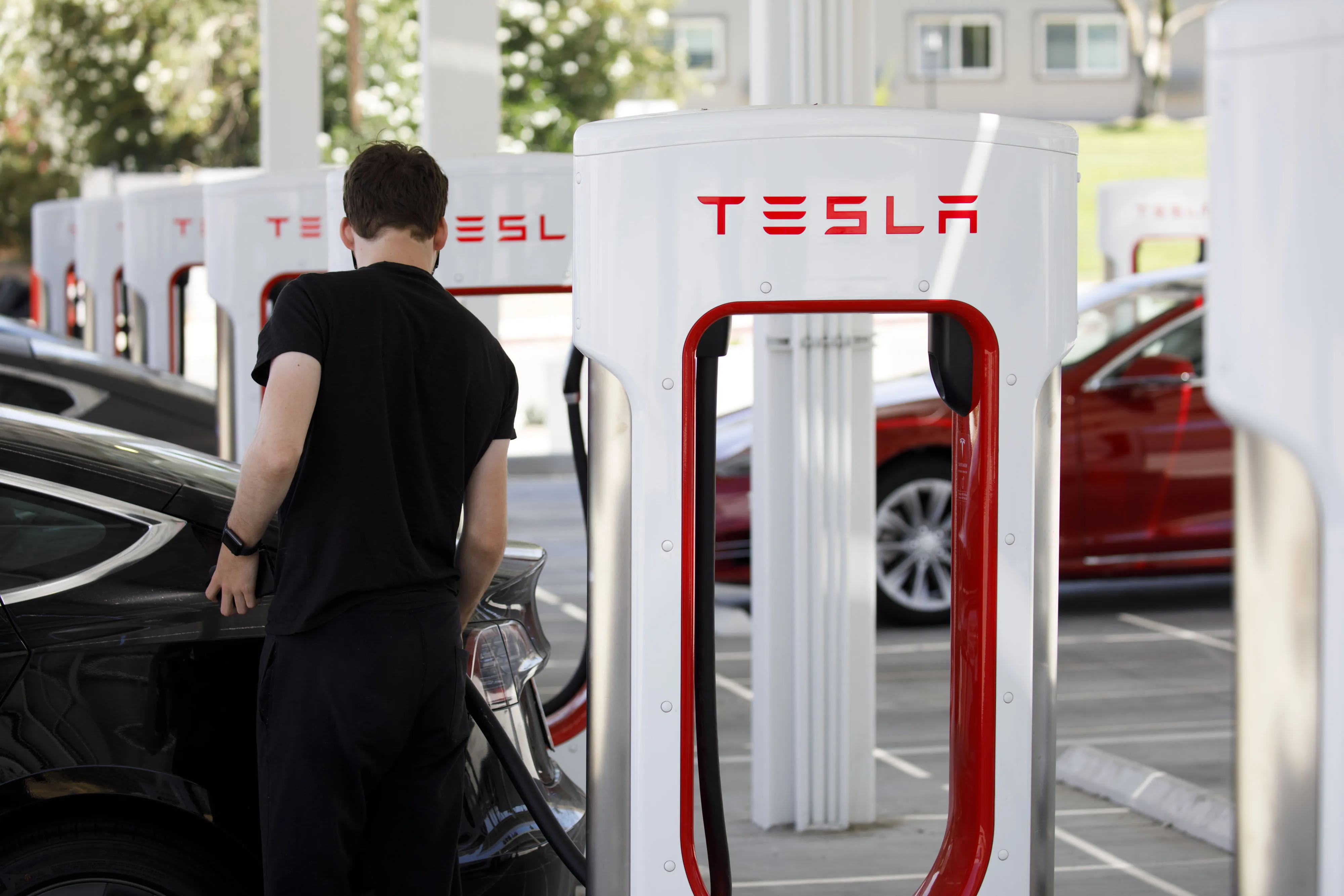A customer plugs in a Tesla Inc. electric vehicle at the Tesla Supercharger station in Kettleman City, California.