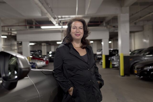 A portrait of Joan Brothers next to her car in a parking garage. 