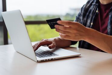 Man shopping online on laptop, entering credit card information to make mobile payment online.