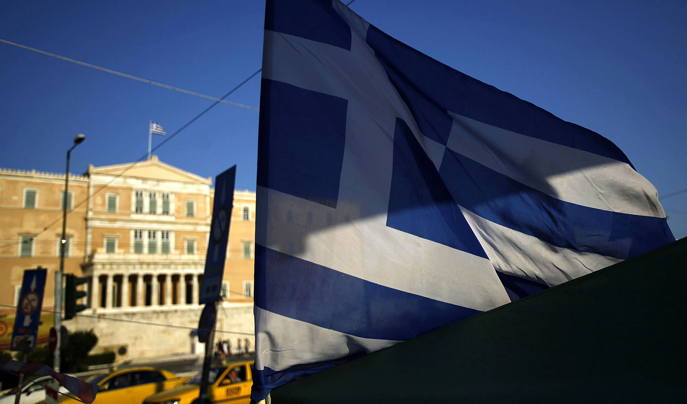 Greek national flag flies in front of the Greek Parliament in Athens.
