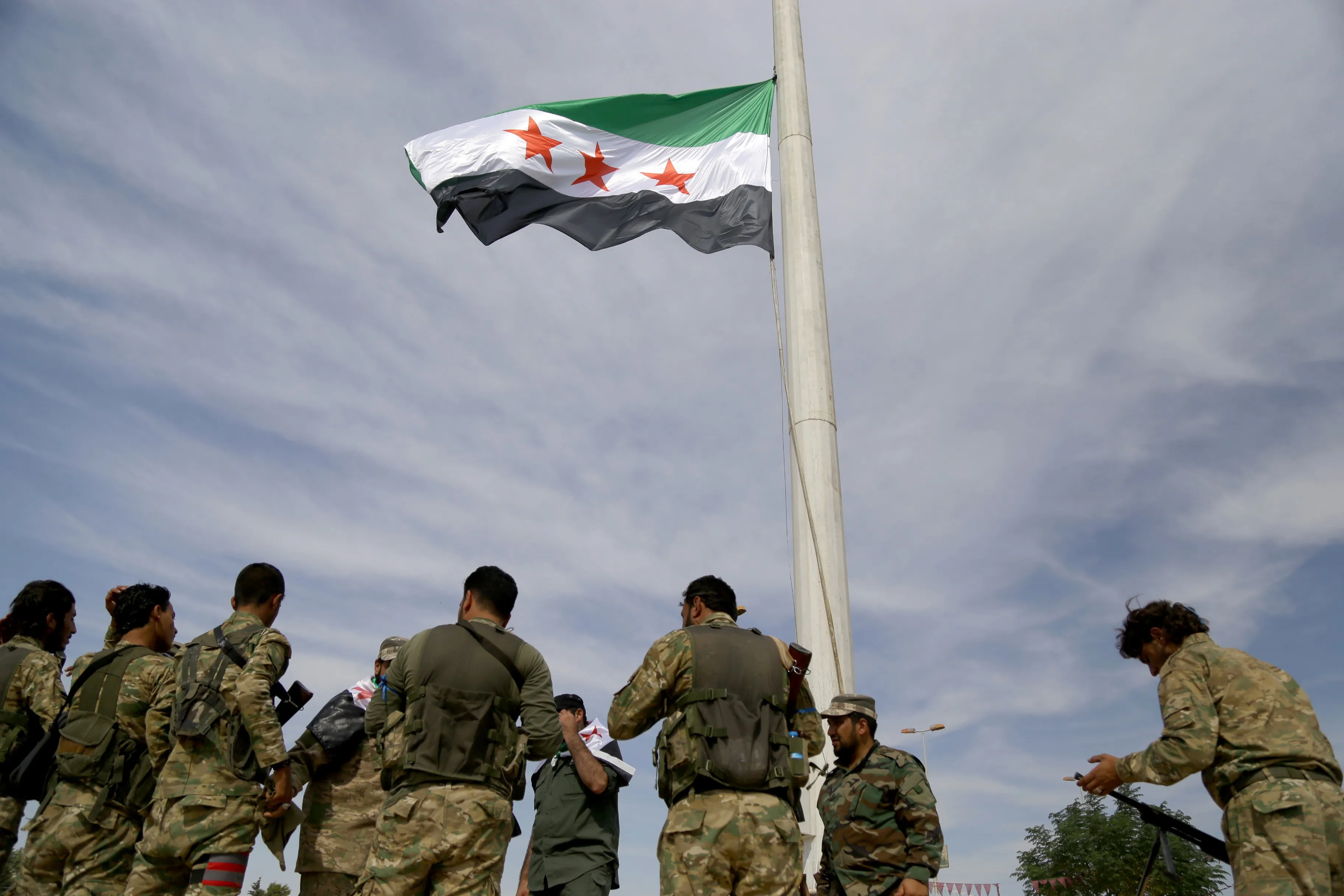 Government forces raise a Syrian natioanl flag in Tal Abyad, northern Syria, on Oct. 14.