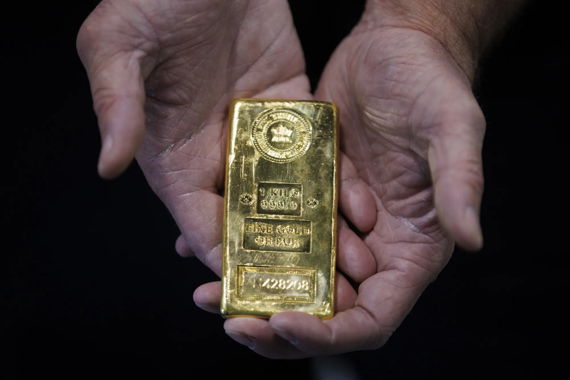An exhibitor holds a 1 kilogram bar of gold at the Prospectors &amp; Developers Association of Canada conference in Toronto on June 14.