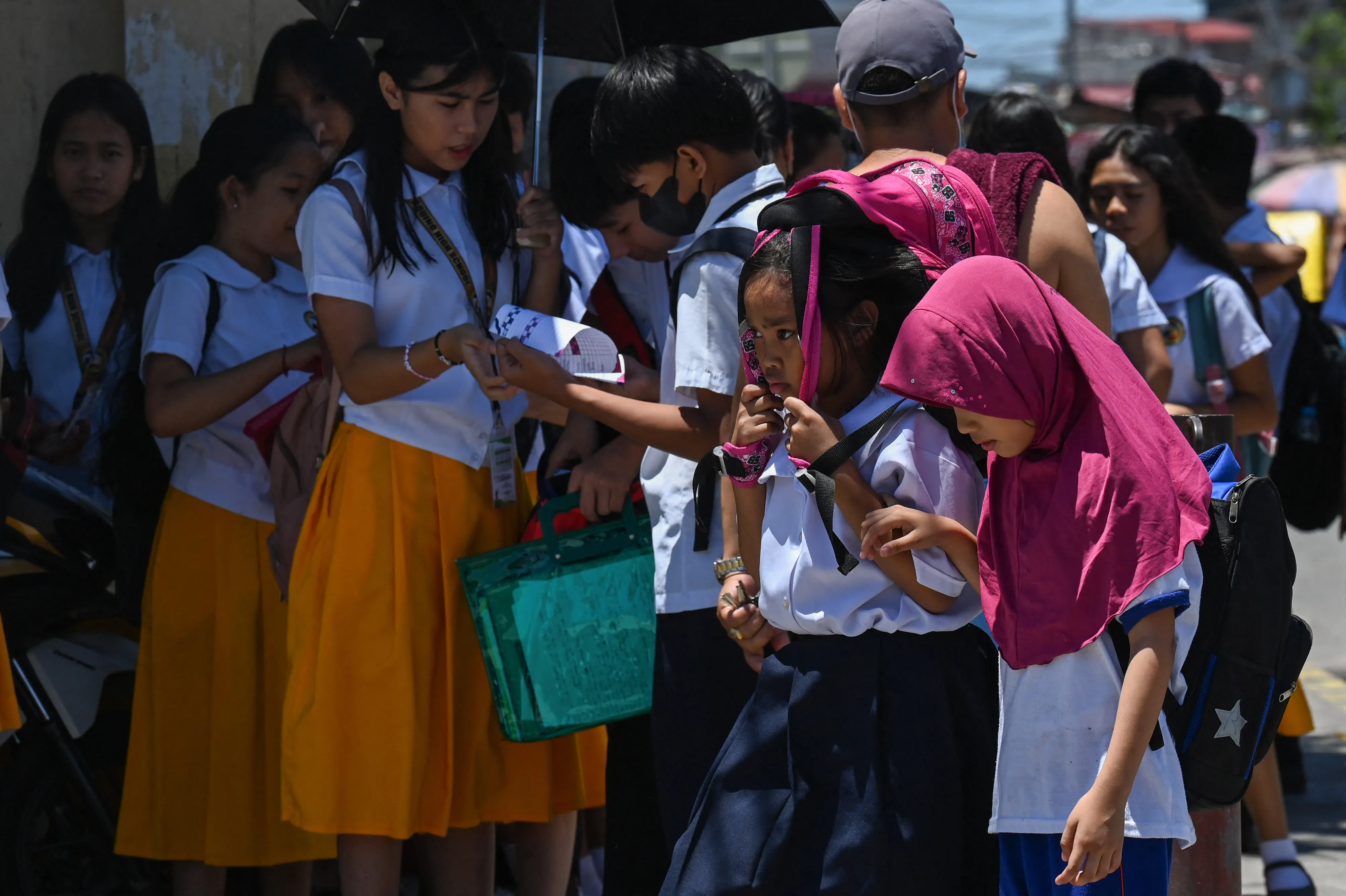 A student uses a bag to protect herself from the sun during a hot day in Manila on April 2.
