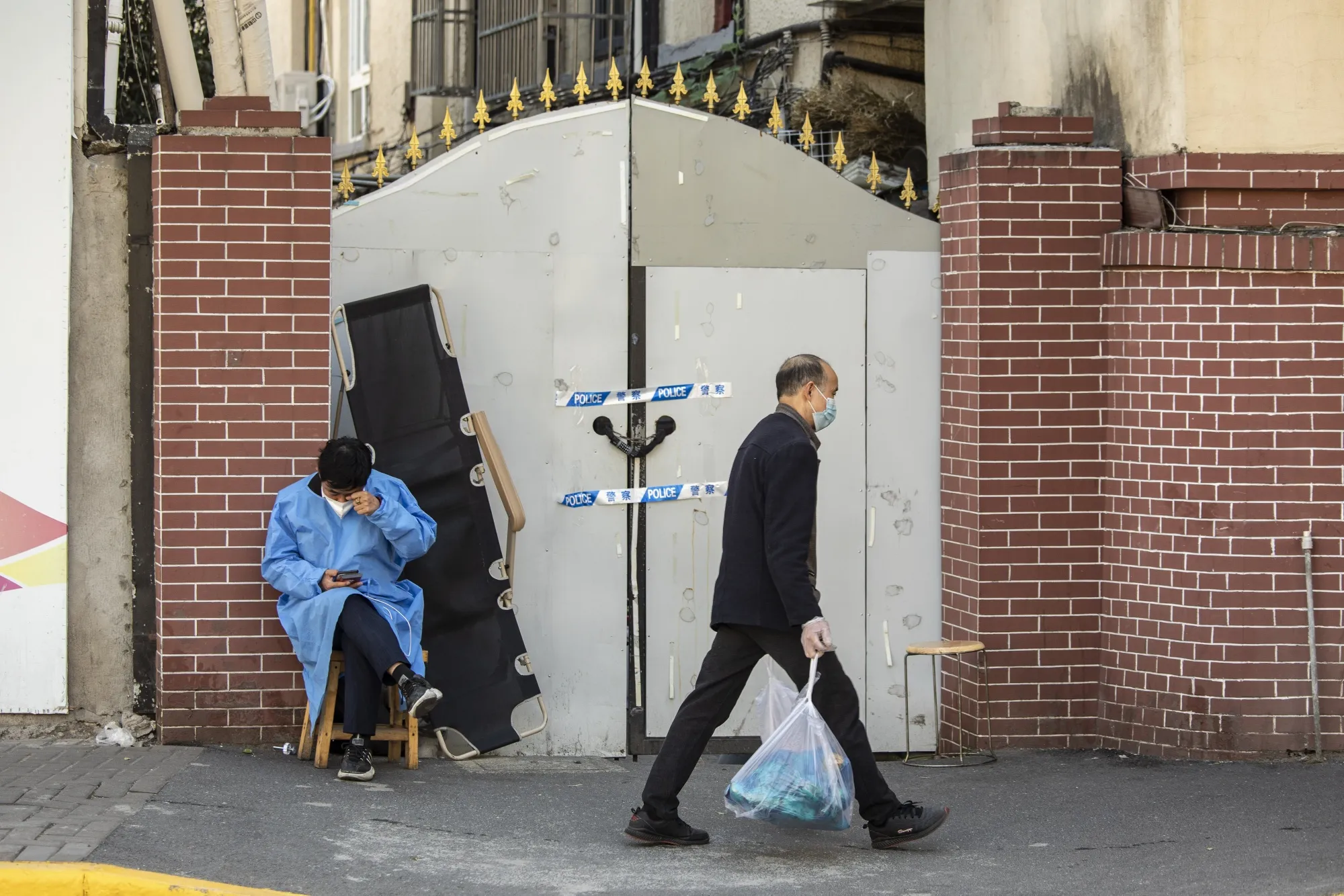 A worker in protective gear guards an entrance to a neighborhood placed under lockdown due to Covid-19 in Shanghai on Nov. 7.