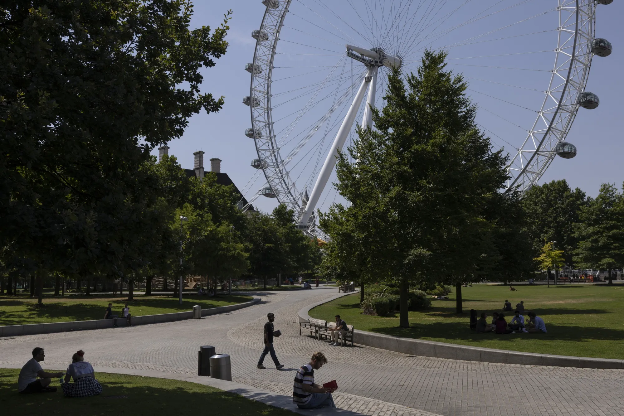 People sit in&nbsp;the shade near the London Eye.