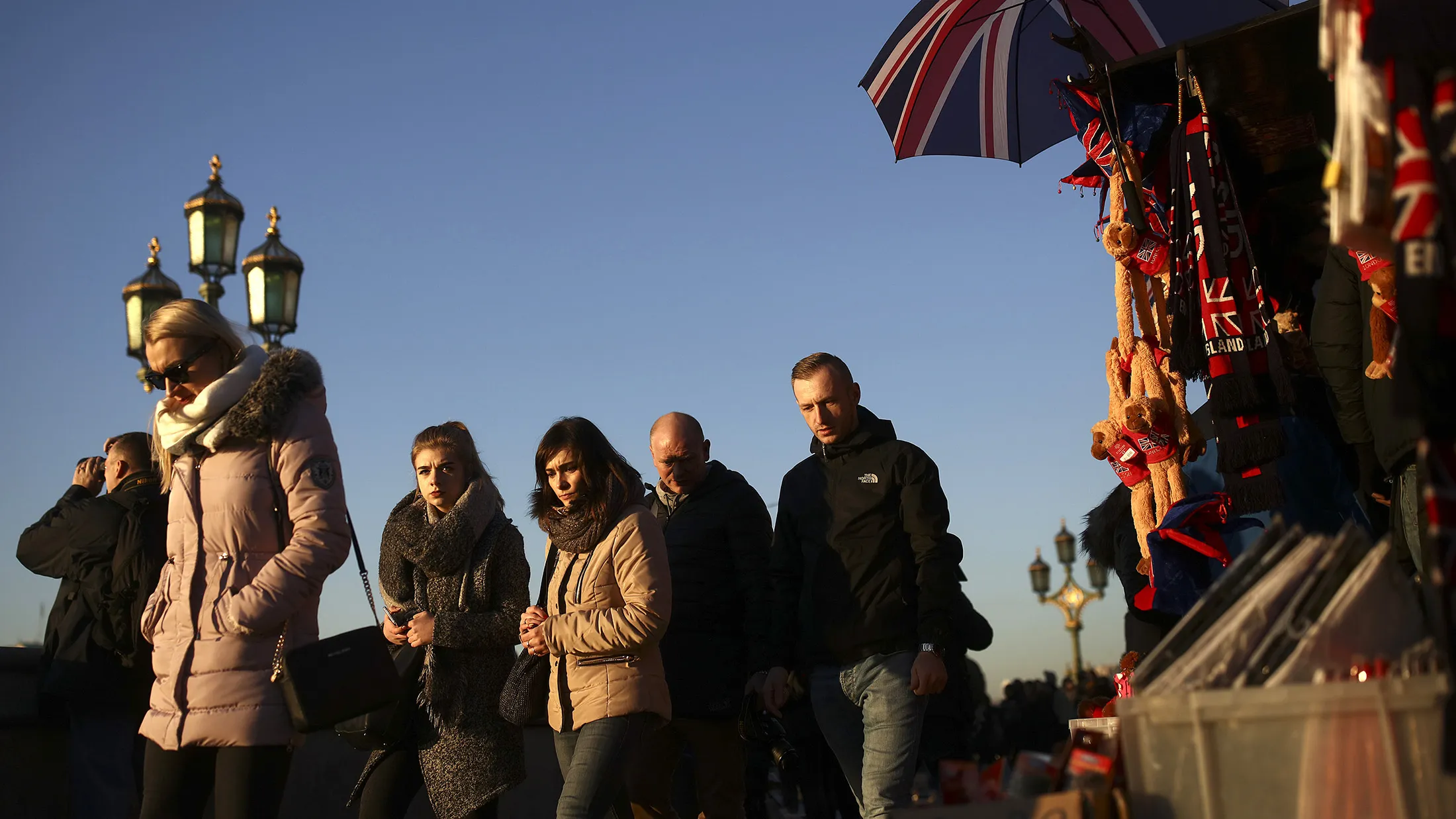 Tourists walk past a souvenir stall on the steps of Westminster Bridge selling paraphernalia decorated with the British Union flag in London, U.K., on Thursday, Dec. 29, 2016. Demand for luxury brands in the U.K. is flourishing, boosted by increased tourism and spending linked to the weaker pound.
