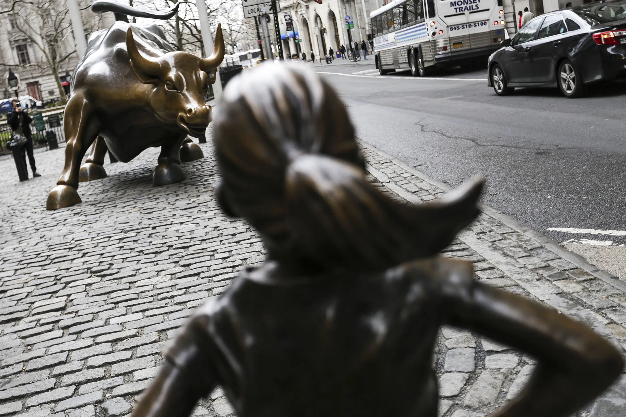 The Fearless Girl statue stands facing the Charging Bull sculpture in the Financial District of New York. 

