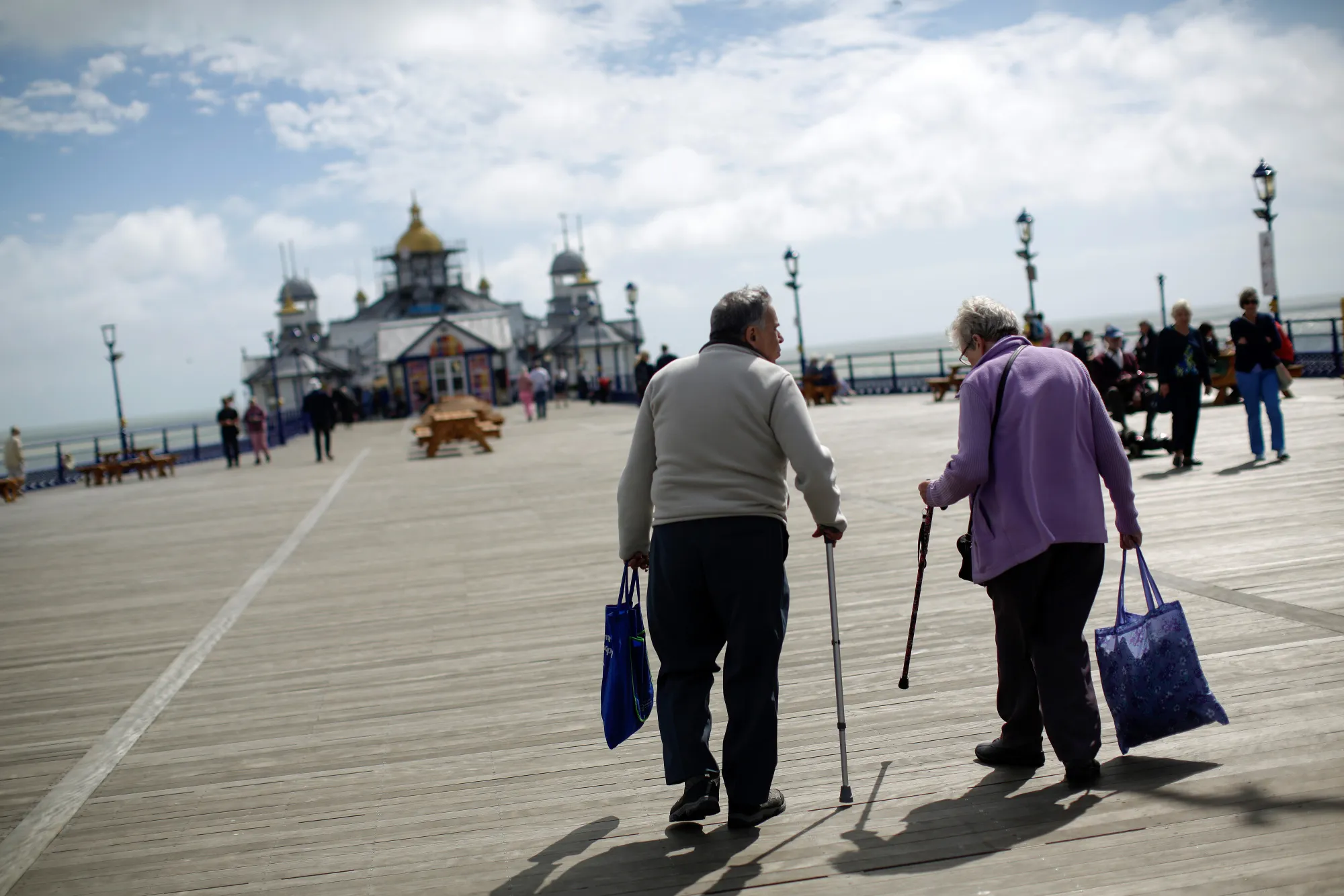 Elderly pedestrians walk using walking sticks on Eastbourne Pier in Eastbourne, U.K., on Monday, Aug. 22, 2016. Pensions are looking like an economic time bomb for Britain, meaning investors had better watch how the nation tries to defuse it.