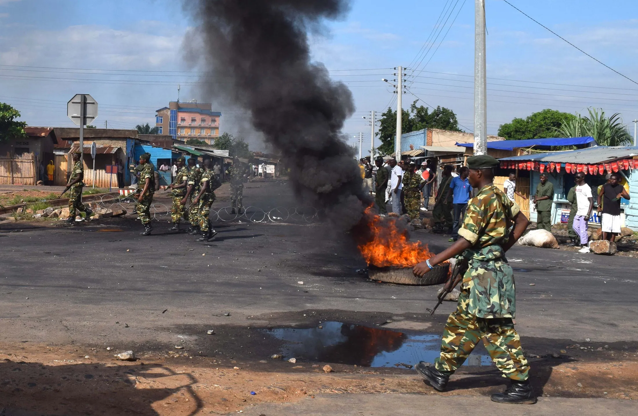Burundian policemen clear the road which closed by protestors during clashes between police and opposition protesters in a street in the capital Bujumbura, Burundi on May 12, 2015.
