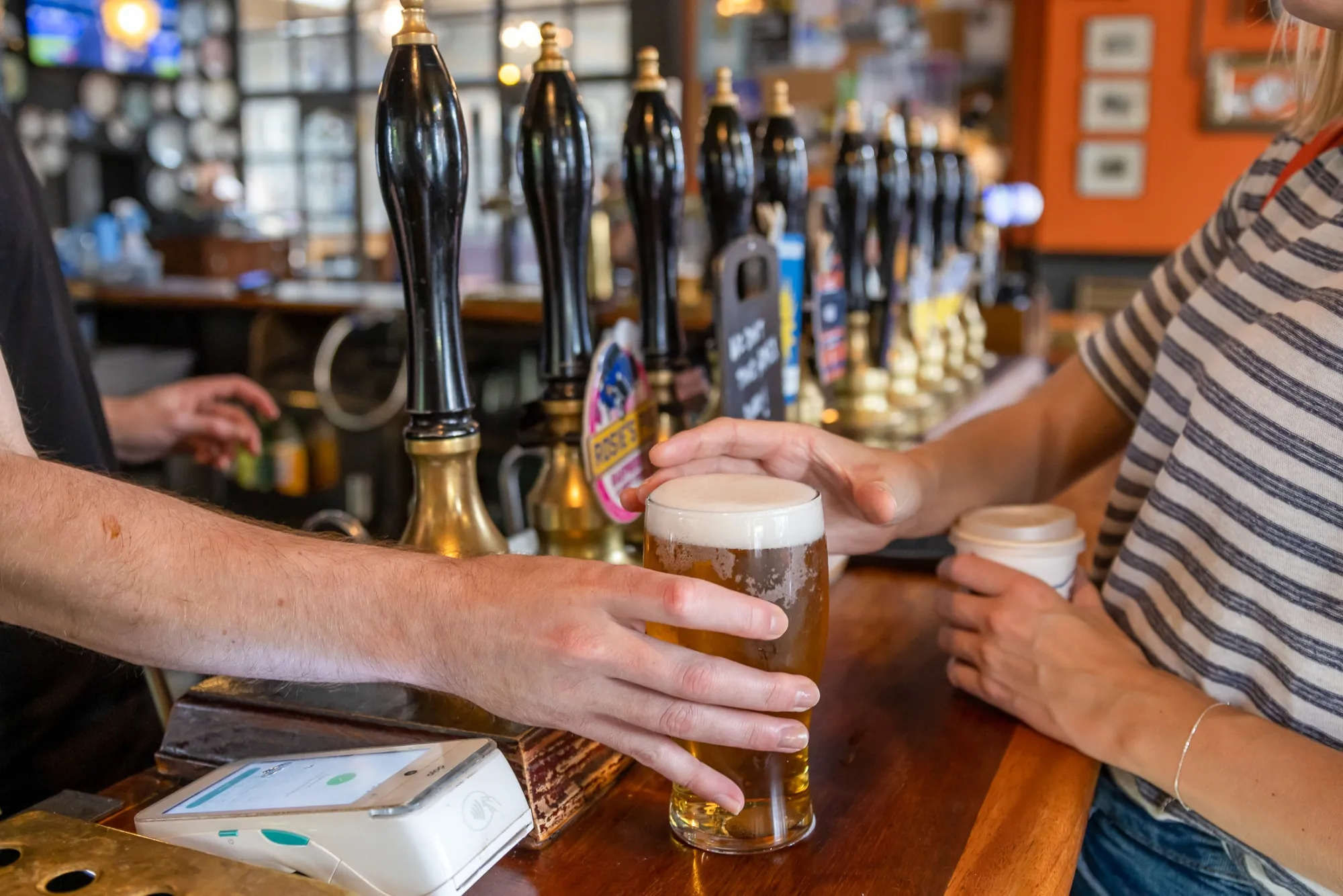 A bartender serves pint of beer to a customer in a&nbsp;pub in London.