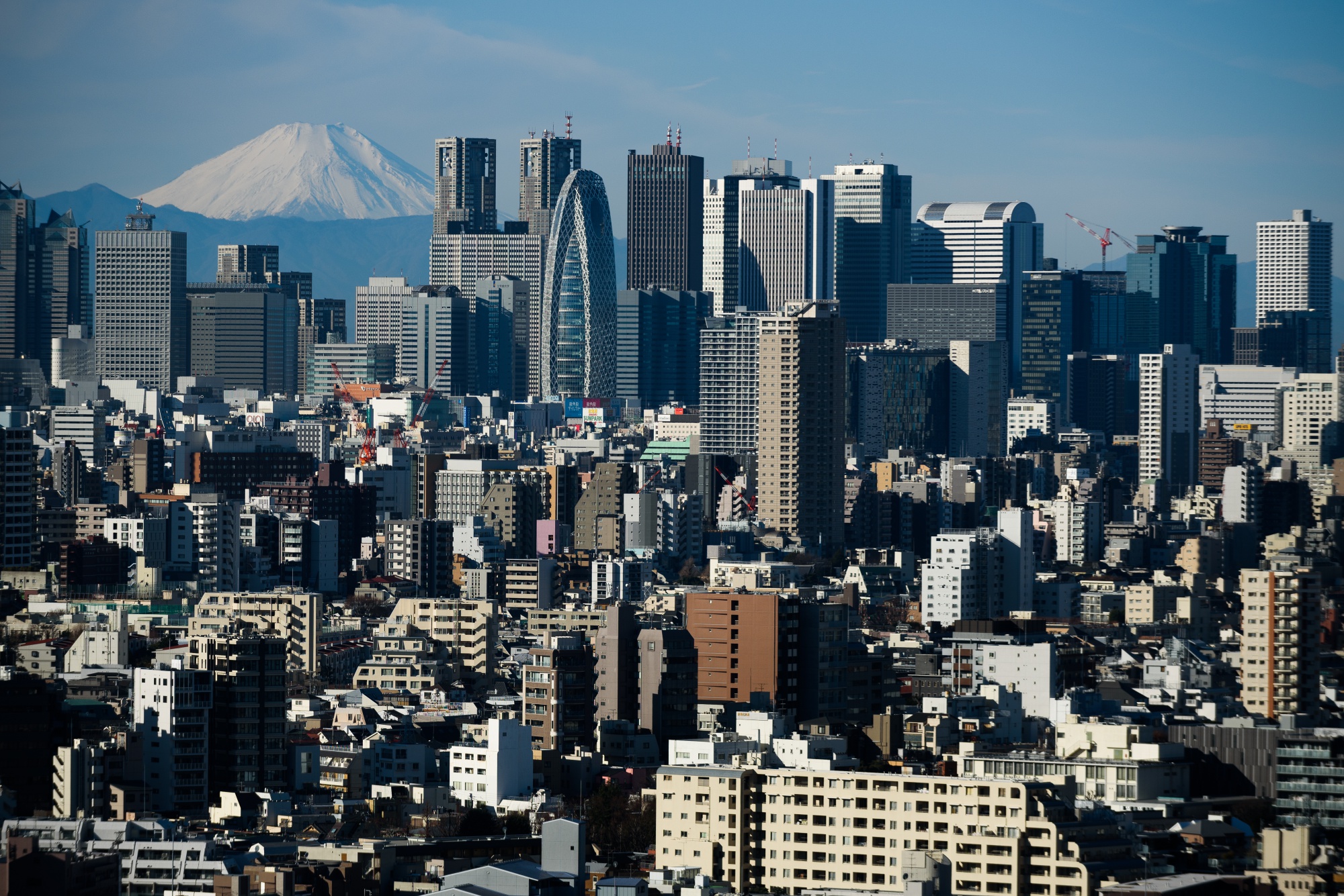 Mount Fuji stands beyond buildings in Tokyo, Japan.