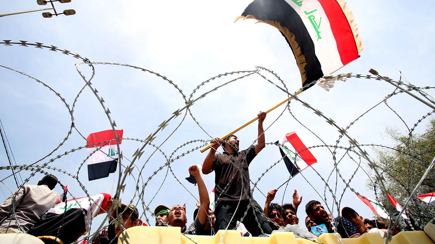 Iraqi supporters of the Sadrist movement hold national flags and shout slogans during a demonstration to press for reforms outside Baghdad's Green Zone on April 26, 2016.
