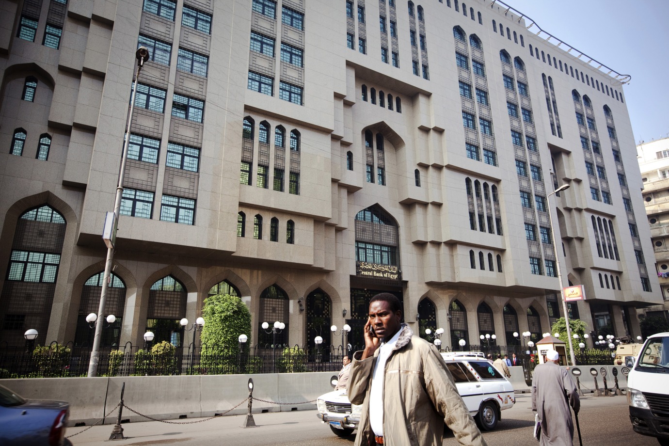 A pedestrian uses his mobile phone as he passes Egypt's central bank in Cairo, Egypt.