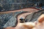A dump truck loaded with ore drives along a haul road in the open pit mine.
