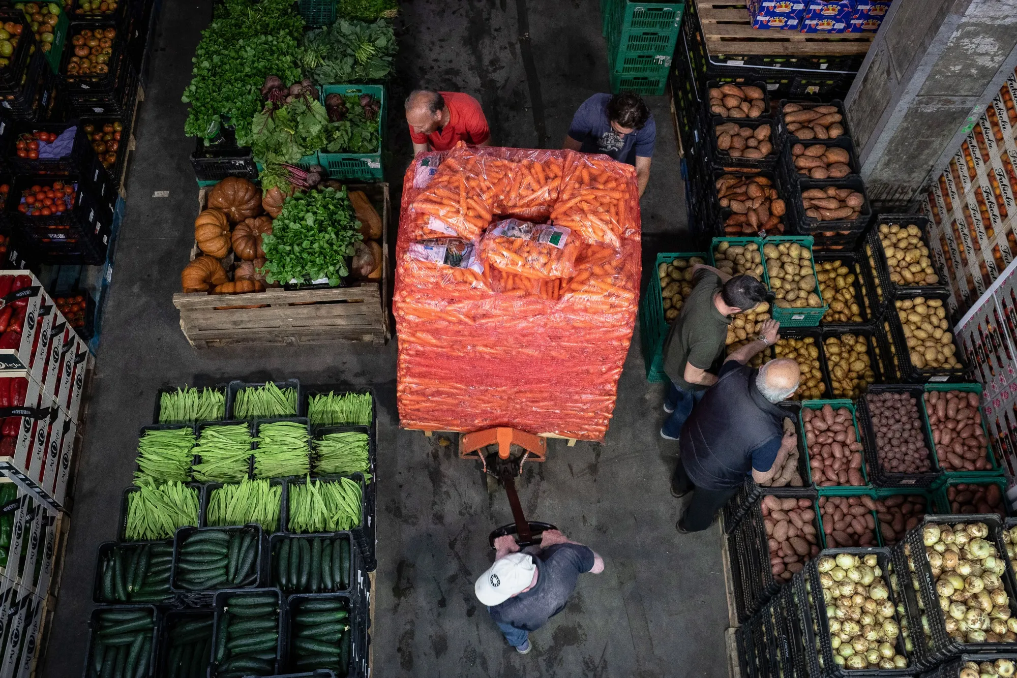Workers push a pallet loader filled with sacks of carrots in Porto, Portugal.
