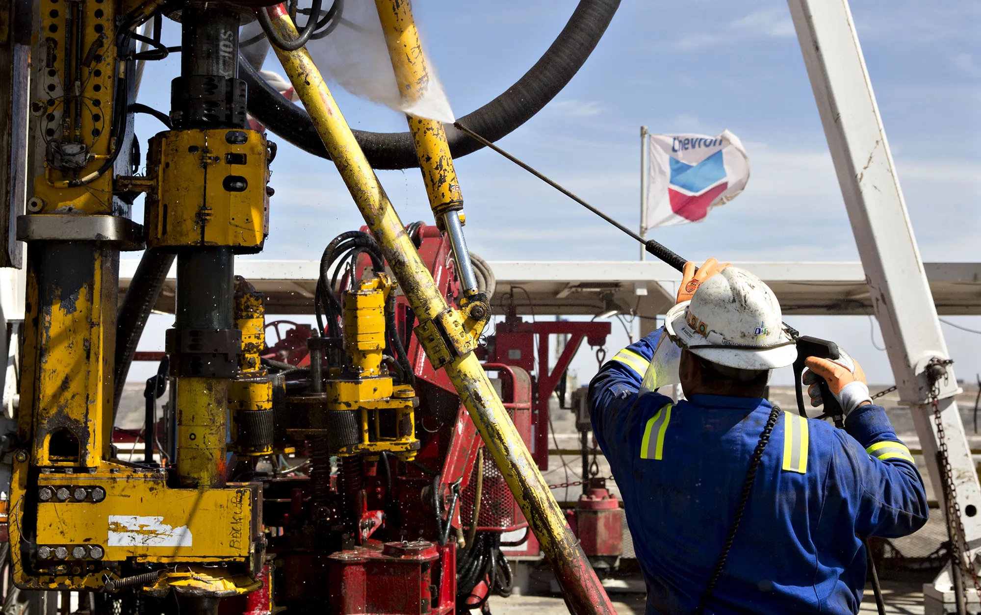 A worker powerwashes the drilling floor of a rig drilling for Chevron Corp. in the Permian Basin near Midland, Texas.