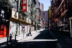 A pedestrian wearing a protective mask walks passed closed businesses in the Chinatown neighborhood of New York, U.S., on&nbsp;May 27.