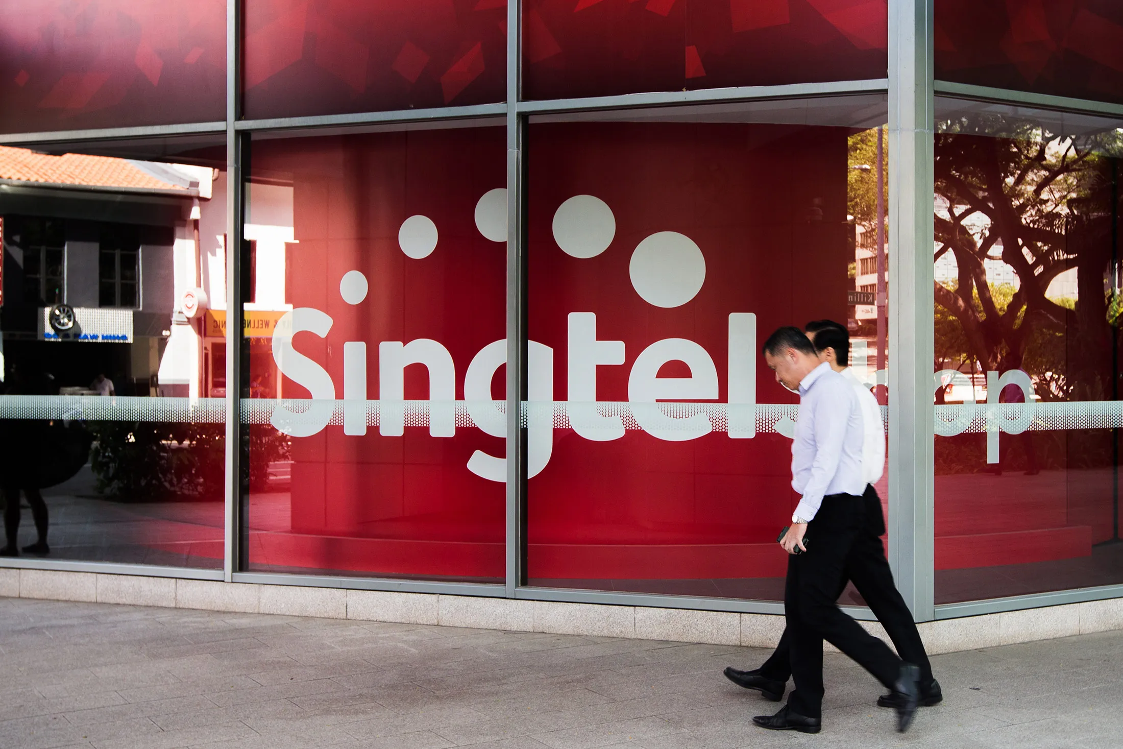 A pedestrian walks past a SingTel store in Singapore, on Monday, Feb. 9, 2016.

