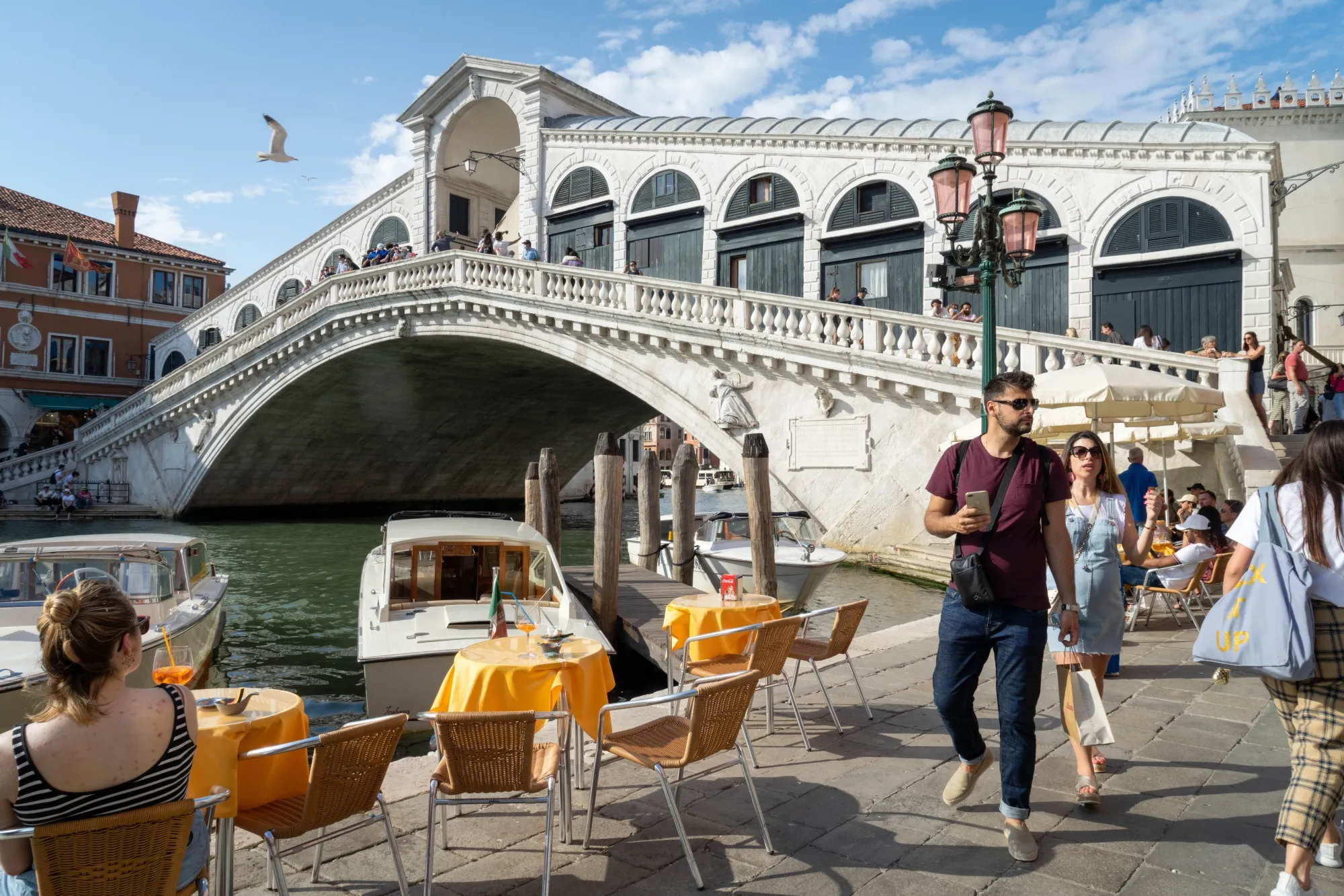 Tourists pass a cafe terrace at the Rialto bridge in Venice&nbsp;on June 5.
