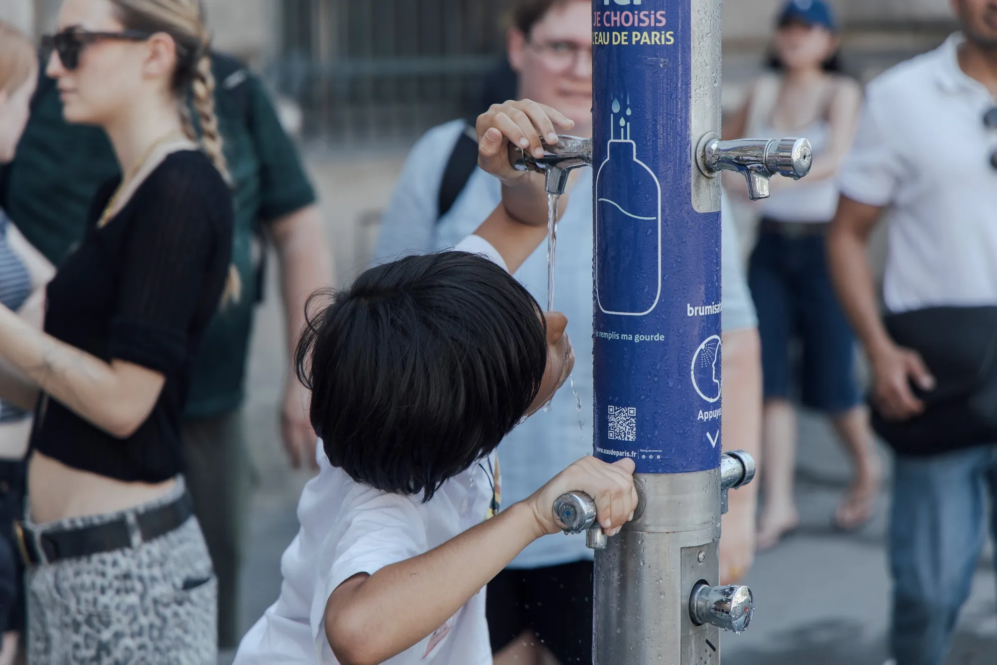A child drinks from a public water fountain during a heat wave in central Paris, France, on Tuesday, July 1, 2025.