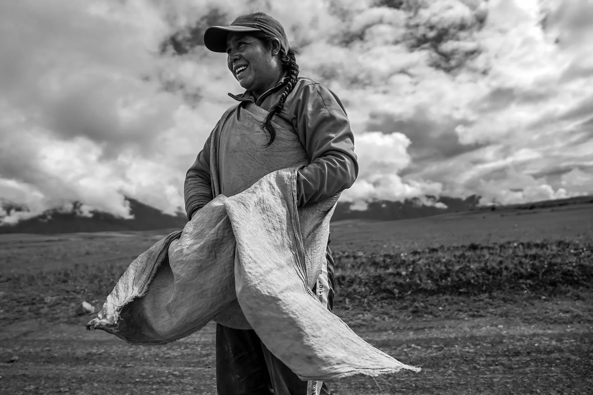 Francisca Ramos stands in a field holding a sack in their hands.