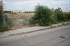 Same field behind a more-and-more dilapidated fence, with giant bushes overgrowing the border